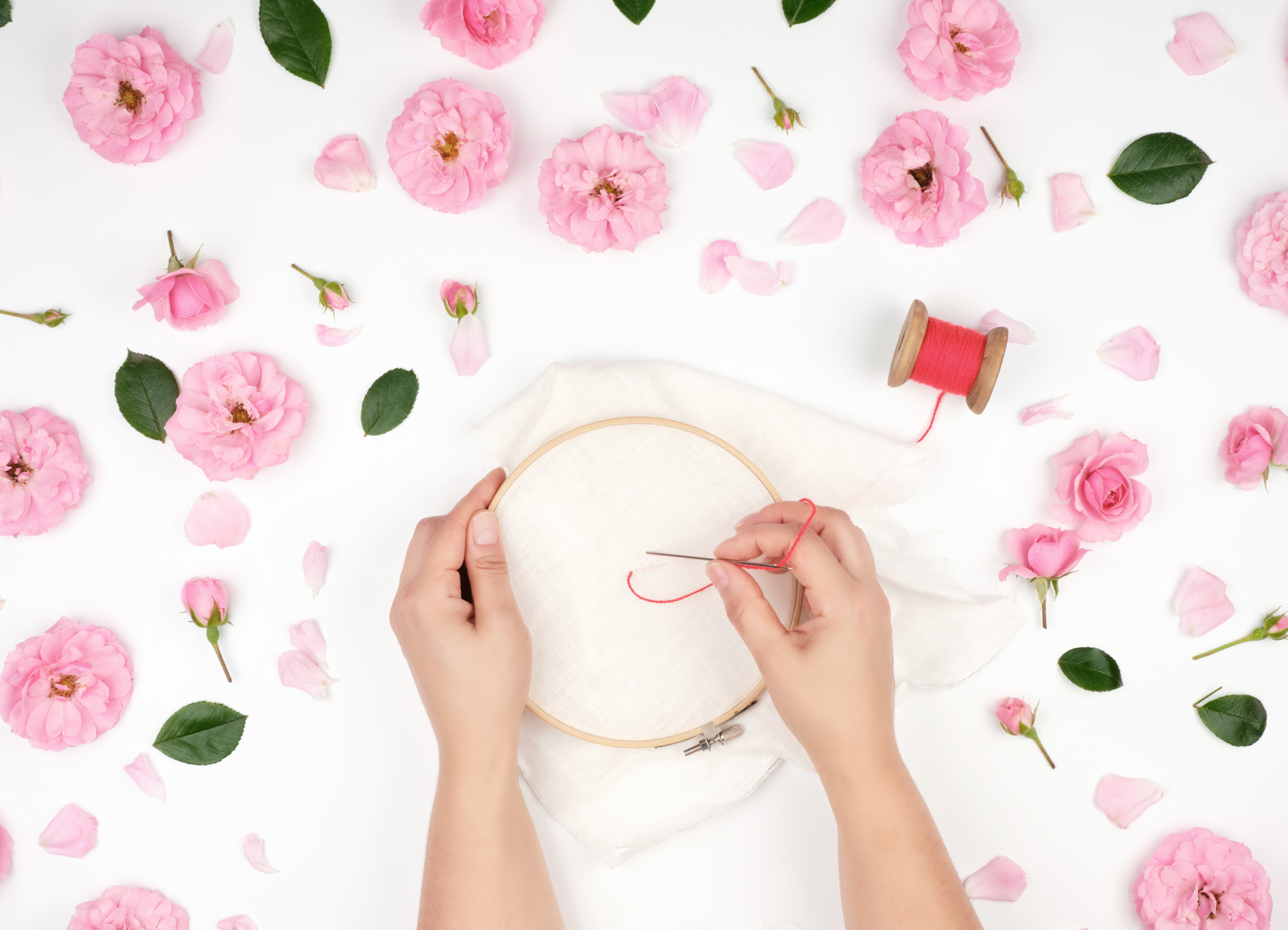 Mano che ricama un fiore su tessuto beige